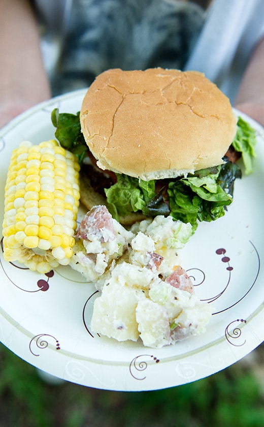 Traditional American summer Barbecue meal with food like burgers, corn on the cob, and potato salad at summer camp
