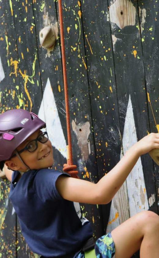 Camper climbing the rock wall in the Ropes Department at Summer Camp.
